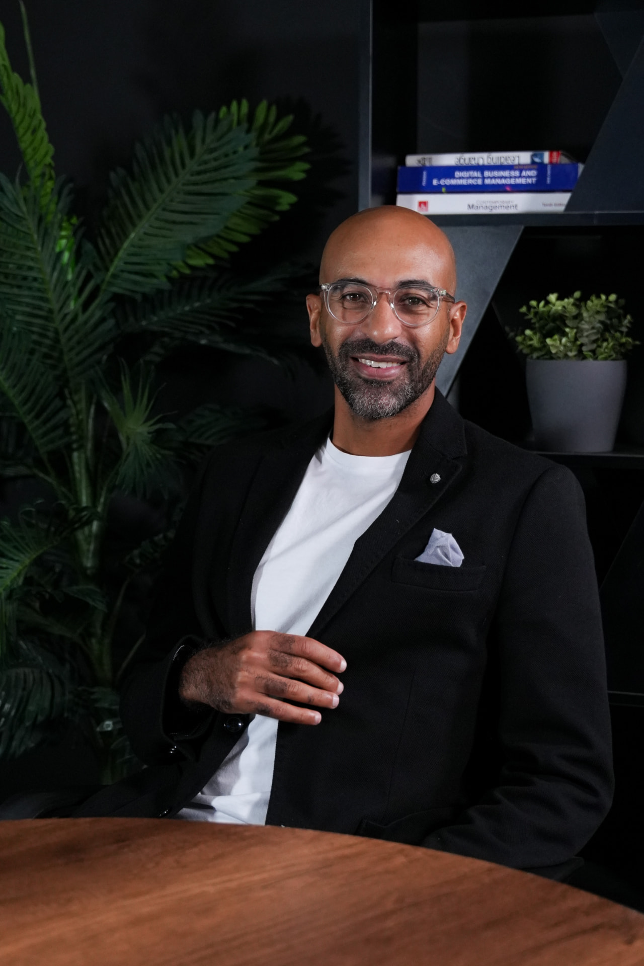 Marawan Nassar seated at a desk, smiling, wearing a black blazer